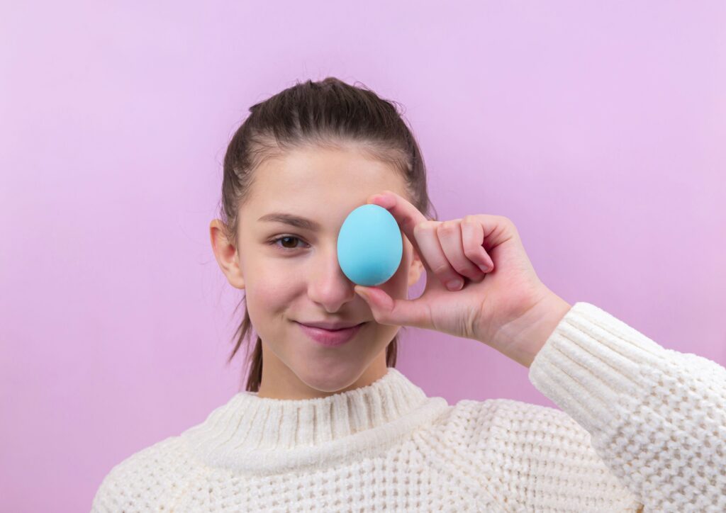 woman in white sweater holding blue egg